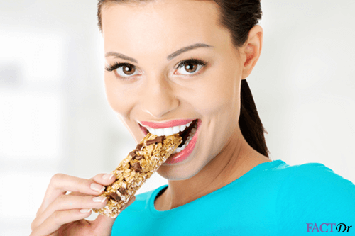 beautiful smiling woman enjoying high fiber energy bar with roughage